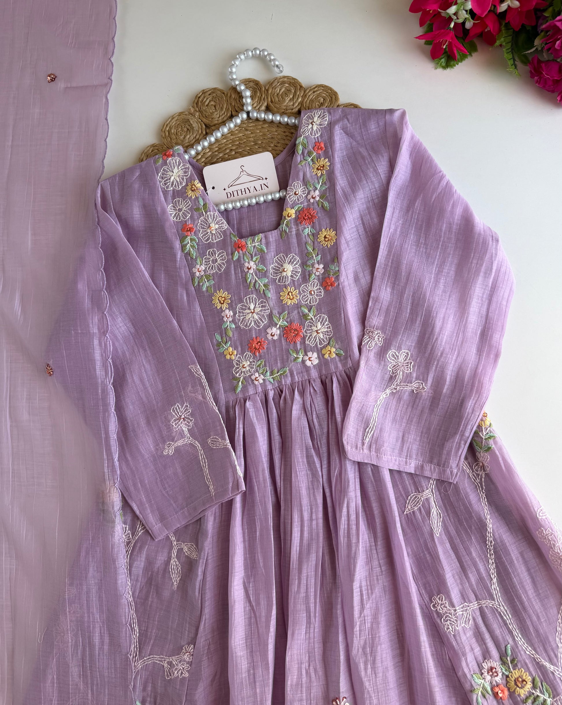 Purple embroidered dress on a hanger with a white background