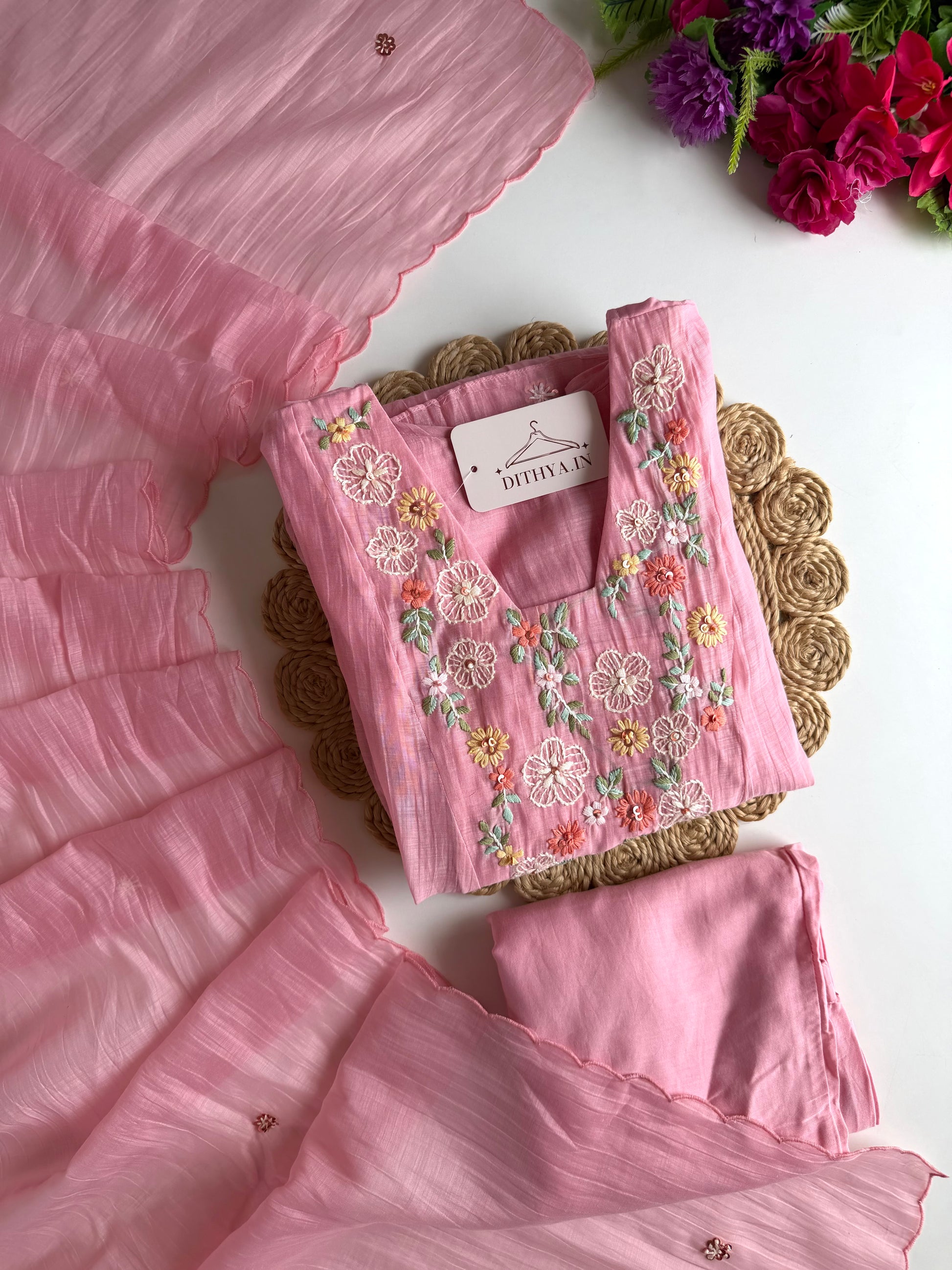 Pink embroidered fabric with a brand label on a white background